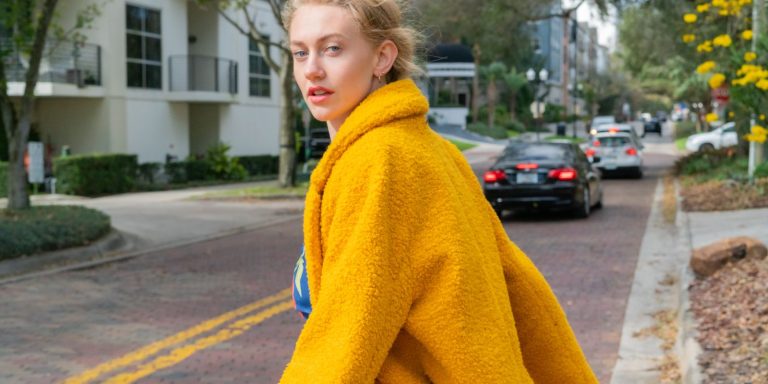 Woman in a bright yellow leather jacket walking confidently down a city street