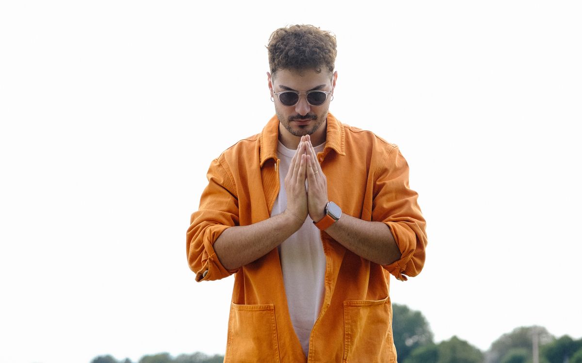Man in a bold orange leather jacket posing on a city street